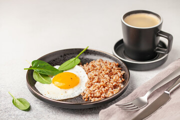 Eggs, buckwheat and spinach on a plate, coffee in a cup. Healthy breakfast.