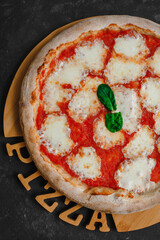 Homemade pizza Margarita on a black background. Pizza Margarita with mutti tomatoes, basil and...