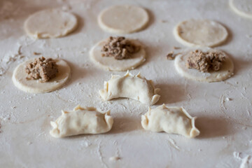 Variki with meat and mushrooms. They lie on the table. Dough.