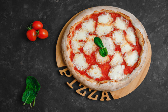 Homemade pizza Margarita on a black background. Pizza Margarita with mutti tomatoes, basil and Mozzarella cheese. Top view,, side view.