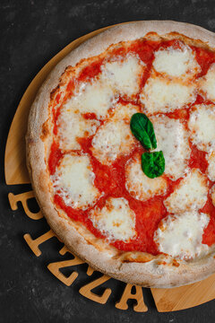 Homemade pizza Margarita on a black background. Pizza Margarita with mutti tomatoes, basil and Mozzarella cheese. Top view,, side view.