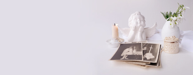 stack of vintage photos, pictures of children of first communion of 1950, candle is lit, spring flowers in vase, concept of family tree, genealogy, childhood memories