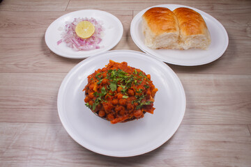 Spicy Misal Pav or Usal Pav is a traditional snack or Chaat food from Maharashtra, India. Served with chopped onion, lemon wedges and farsan. Selective focus with copy space