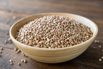Green buckwheat in a bamboo bowl on wooden table background, healthy vegan food