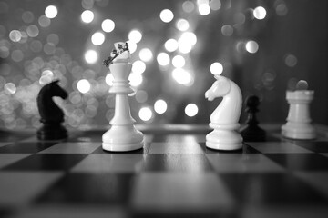 chess pieces, queen in crown white and black on a chessboard, concept of leadership and teamwork in...
