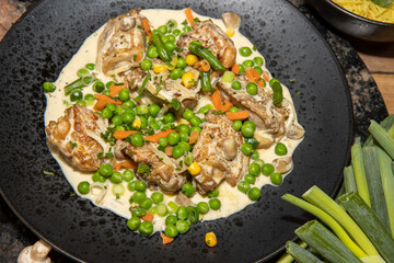 A delicious plate of Creamy Chicken with Spring Vegetables on a wooden kitchen table