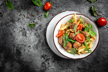 Italian pasta. penne pasta with meatballs in tomato sauce in a white craft bowl on a grey stone background. banner, menu recipe place for text, top view