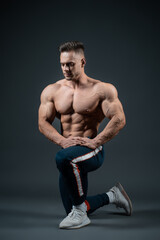Obraz na płótnie Canvas young handsome sportsman bodybuilder posing on dark background