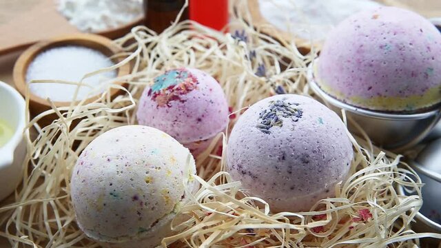 Making bath fizz bombs at home concept. All the ingredients on table on wood spoons: cornstarch, essential oil, dye, citric acid, baking soda, dry herbs, round metal pressing molds.