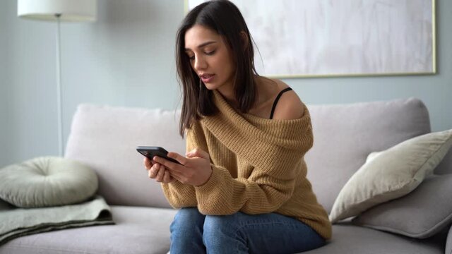 Indian mixed-race woman using smart phone surfing social media, texting messages