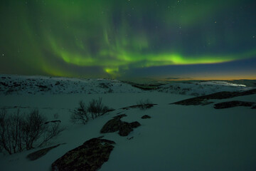 Fototapeta na wymiar Northern lights in the sky. Snowy tundra at night.