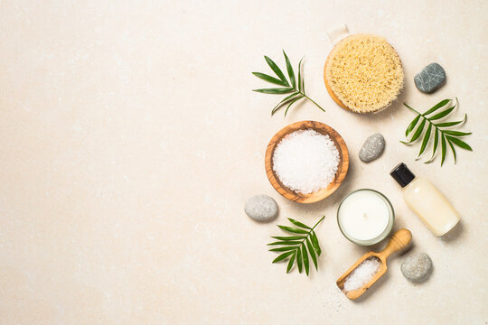 Spa background. Spa product composition with palm leaves, cosmetic and sea salt at stone table. Flat lay image.