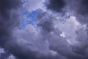 Naklejka na ściany i meble Blue sky behind dark violet storm clouds background texture, thunderstorm