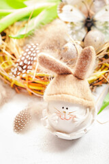 Spring Easter holiday white background with tulips, quail eggs, butterflies, bunny and feathers in a nest. Banner with copy space. Top view