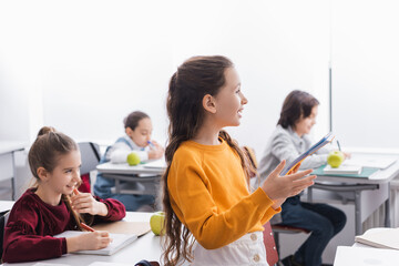 Smiling schoolkid holding notebook during lesson in class