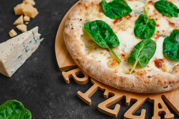 Homemade pizza with four cheeses, gorgonzola, parmesan, camembert, emmental and spinach on a dark background. Top view, side view