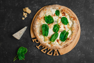 Homemade pizza with four cheeses, gorgonzola, parmesan, camembert, emmental and spinach on a dark background. Top view, side view