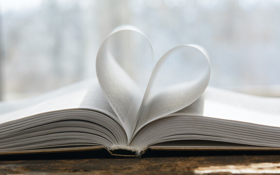 An open book. The pages are folded in the shape of a heart. Blurred background. Concept-romance, Valentine's Day