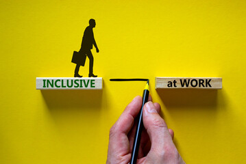 Inclusive at work symbol. Wooden blocks with words 'Inclusive at work' on beautiful yellow...