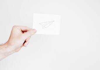 Man holding a paper with a drawing of an airplane