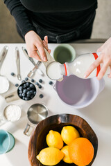 Woman pouring milk into measuring cup and making muffins