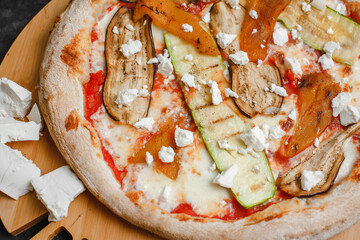 Homemade vegetarian pizza with grilled vegetables. Tomato sauce, bell pepper, eggplant, zucchini, mozzarella and cheese on a dark background. Top view, side view