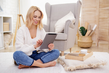 portrait of cute blond woman using tablet pc in living room