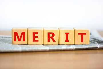 Merit symbol. Wooden cubes with the word 'merit'. Beautiful white background, copy space. Newspaper. Business and merit concept.