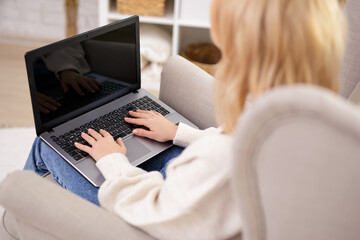 Fototapeta premium back view of young woman using laptop with blanck screen at home