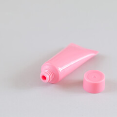 Pink open cosmetic tube on gray background