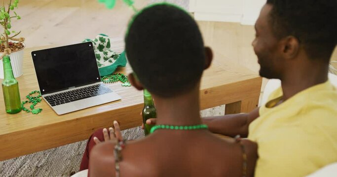 African american couple making st patrick's day video call wearing deely boppers drinking beer
