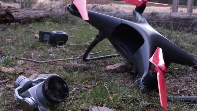 Crashed quadcopter drone with broken propellers lying on grass after failed flight