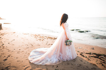 Romantic beautiful bride in white dress posing on the background sea