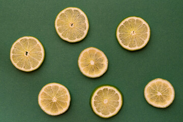 Seven slices of lime on a green background. Top view. Minimalism.