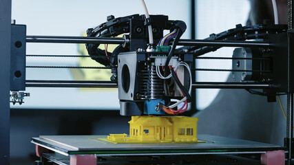 3d Printer printing yellow small house with engineer constructor in background at pc model