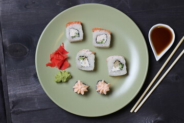 Salmon and crab rice rolls, marinated ginger, vasabi on green plate