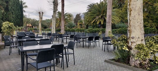 An outdoor cafe with empty tables and chairs on the embankment. Spring day.