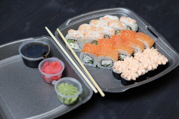 Roll set in box safe delivery with chopstick, sauce on black background