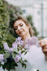 Naklejka premium Portrait of a beautiful inspired sweet romantic gentle pretty bride a young woman in a wedding dress walking and standing alone in a blooming spring green park, selective focus
