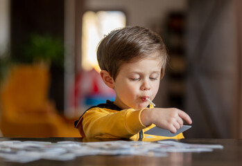 little boy learns words from cards under the ABA therapy program at home at the table