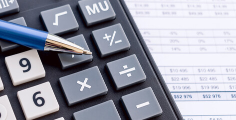 Photo of a calculator with a handle on it that lie on financial documents. Close-up photo
