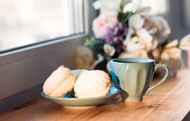 Blue cup of coffee with marshmallows on the windowsill. Early morning