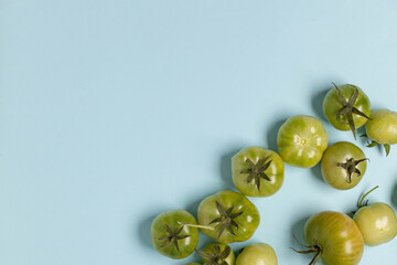 Fresh green tomatoes of different sizes heap on a blue background with copy space. Food concept. Vegetables