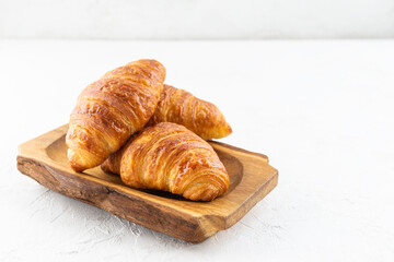 Croissants in a wooden bowl on a light background.