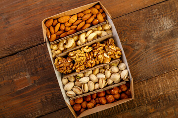 Assorted nuts in packaging on a brown wooden table. Copy space
