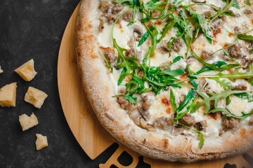 Homemade pizza with chicken and mushrooms. Cream sauce, mozzarella, parmesan and arugula on a dark background. Top view, side view