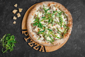 Homemade pizza with chicken and mushrooms. Cream sauce, mozzarella, parmesan and arugula on a dark background. Top view, side view