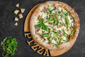 Homemade pizza with chicken and mushrooms. Cream sauce, mozzarella, parmesan and arugula on a dark background. Top view, side view