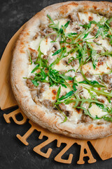 Homemade pizza with chicken and mushrooms. Cream sauce, mozzarella, parmesan and arugula on a dark background. Top view, side view