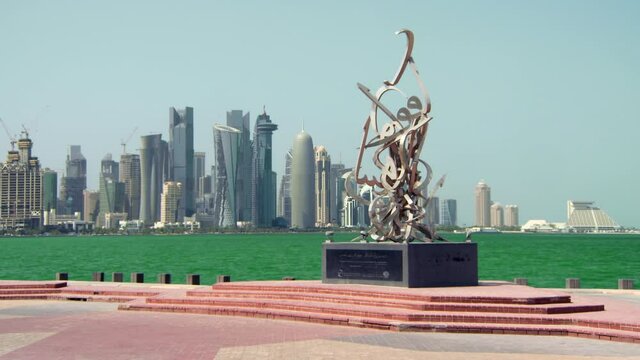 Large Metal Calligraphic Sculpture In Front Of Green Bay And Towering Cityscape With Skyscrapers In Sunshine